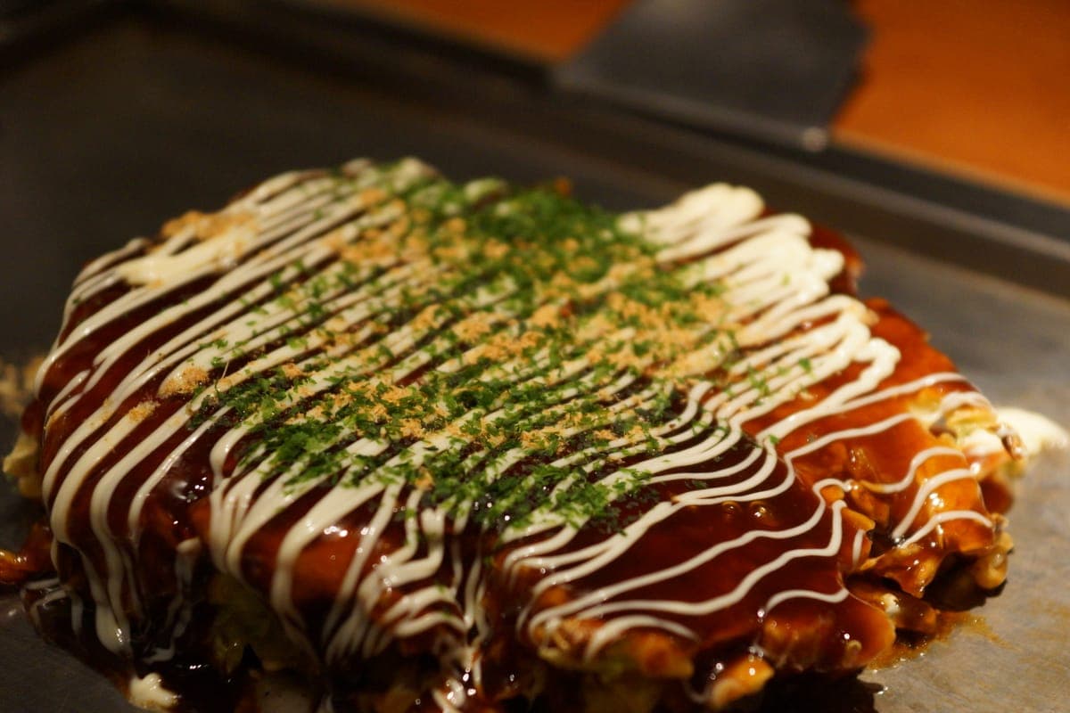 Okonomiyaki topped with sauce, mayonnaise and green laver