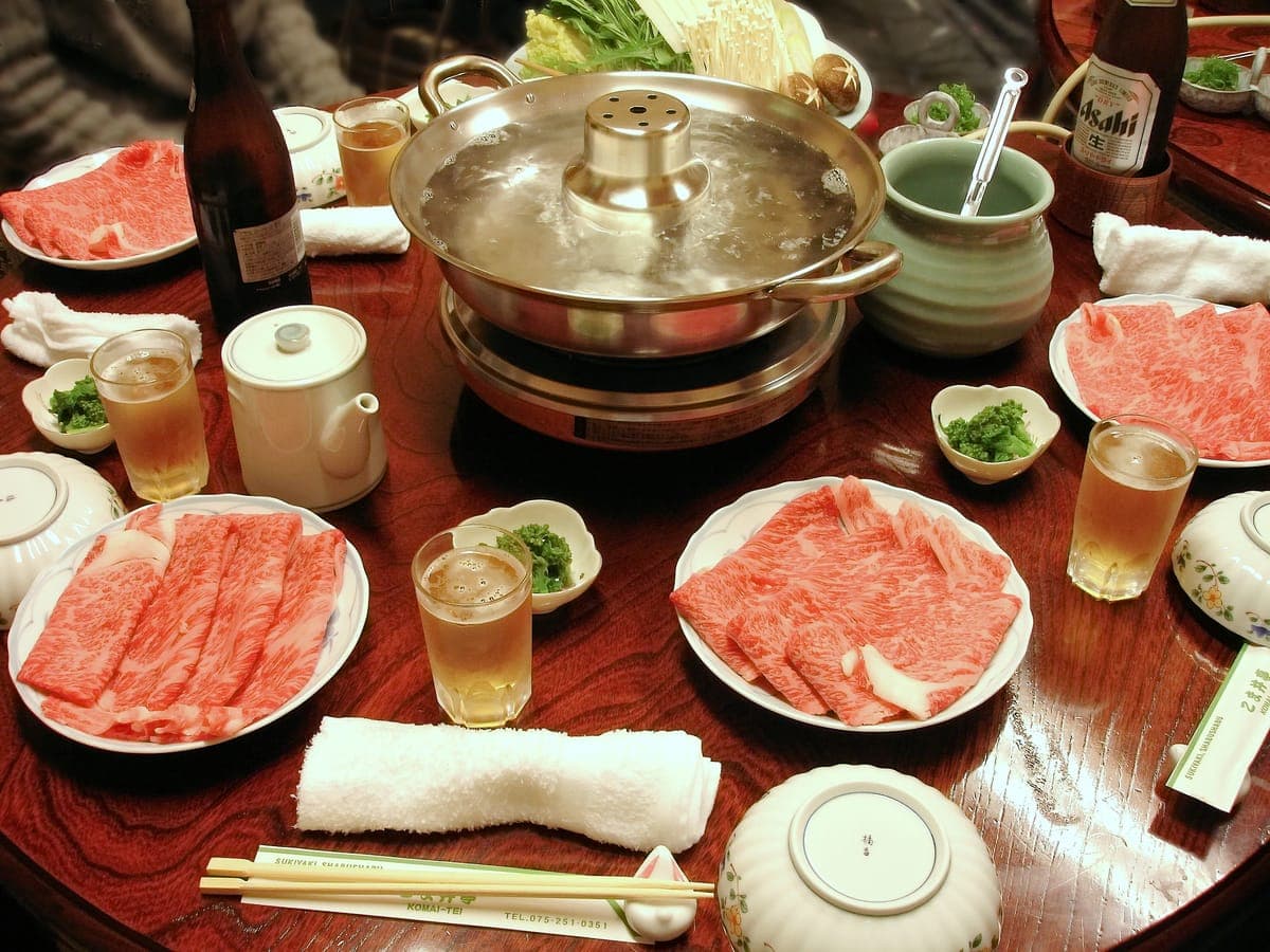 Shabu-shabu table with a hot pot and plates of thinly sliced beef