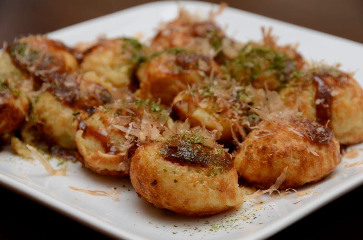 Takoyaki on a plate, topped with sauce and bonito flakes